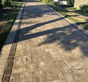 Herringbone paver driveway with contrasting clay brick soldier-course border.