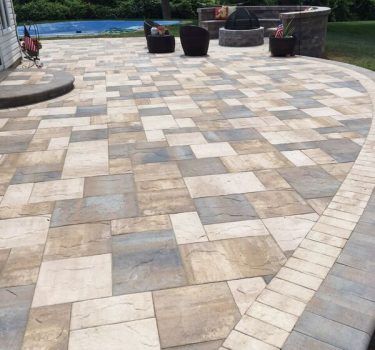 Paver patio with seat-wall and planting borders, warm evening light.