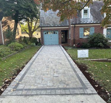 Brick border detail along a long cobblestone paver driveway.