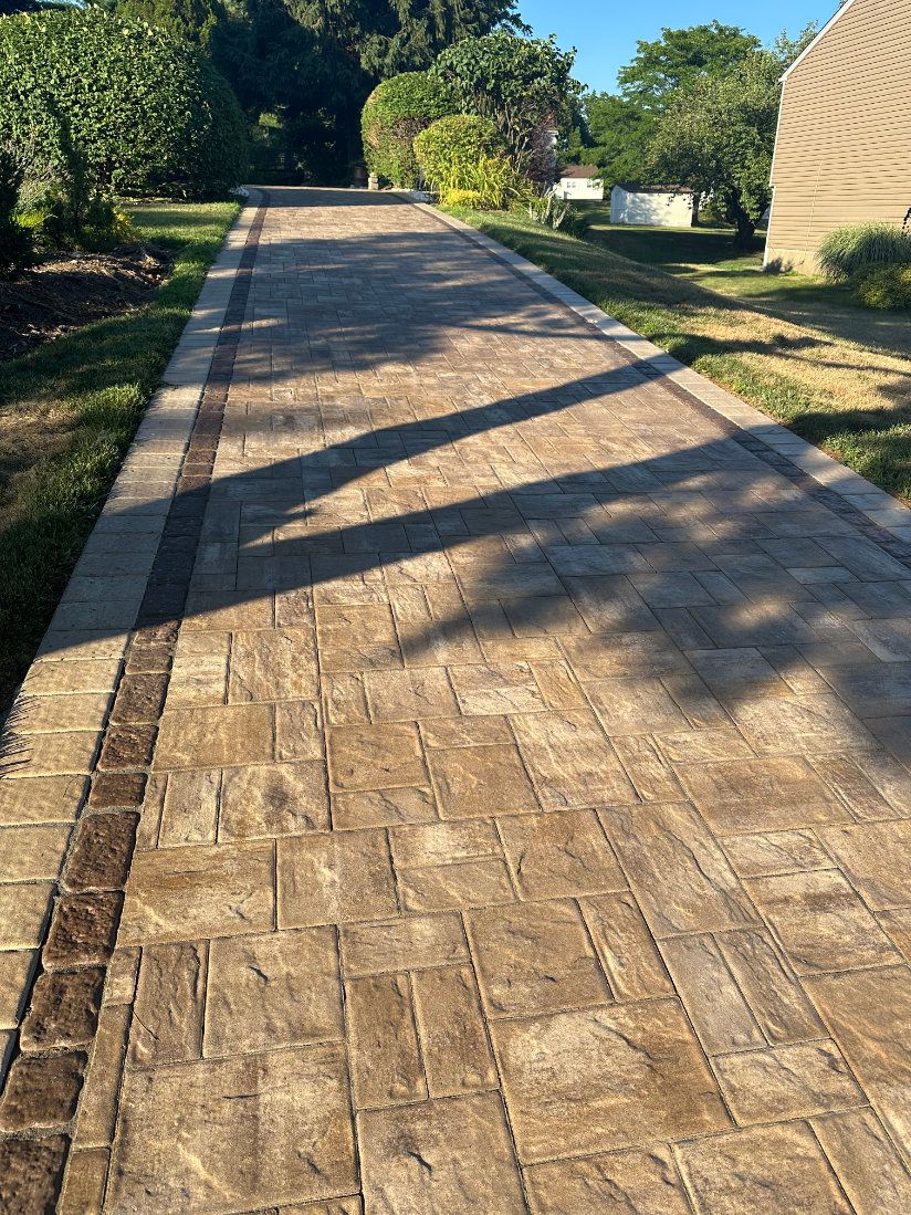 Brick paver walkway crossing a residential yard in afternoon shadow and sun.
