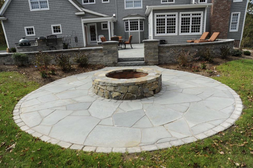 Bluestone circular patio anchored by a cut-stone fire pit with a paver surround.
