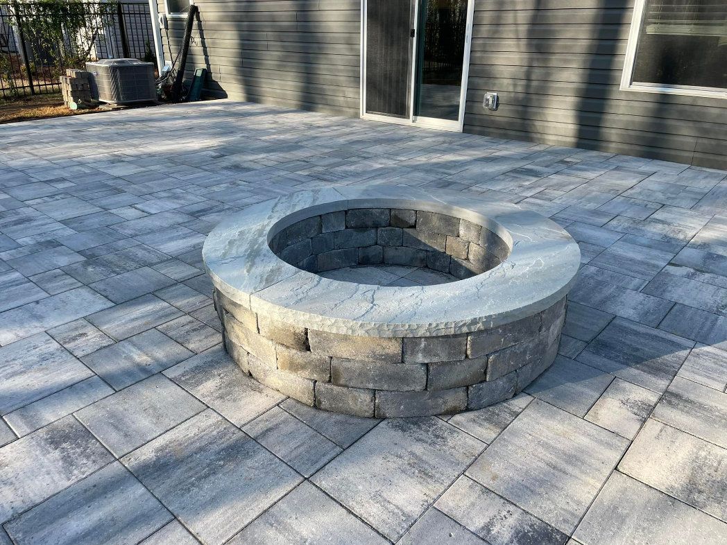 Circular flagstone patio with a stone firepit and stepped paver surround.