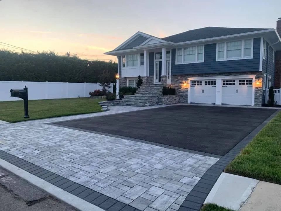 Dusk view of a home with a new paver driveway edged by a stone retaining wall.