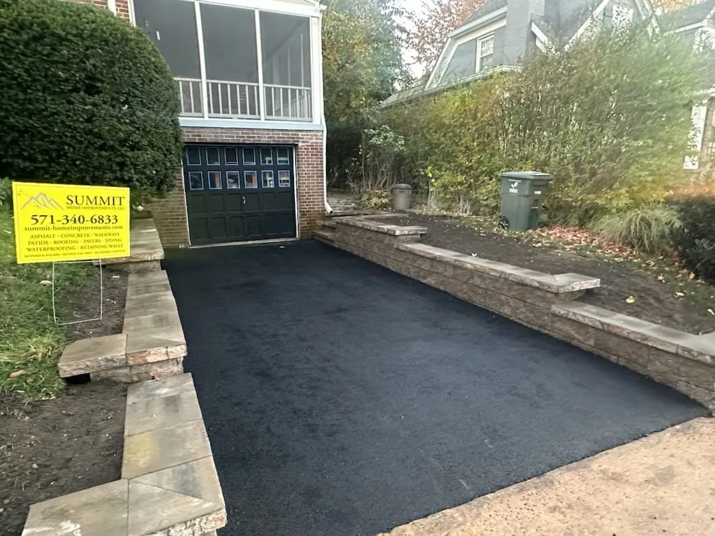 Fresh asphalt driveway between twin stacked-stone retaining walls