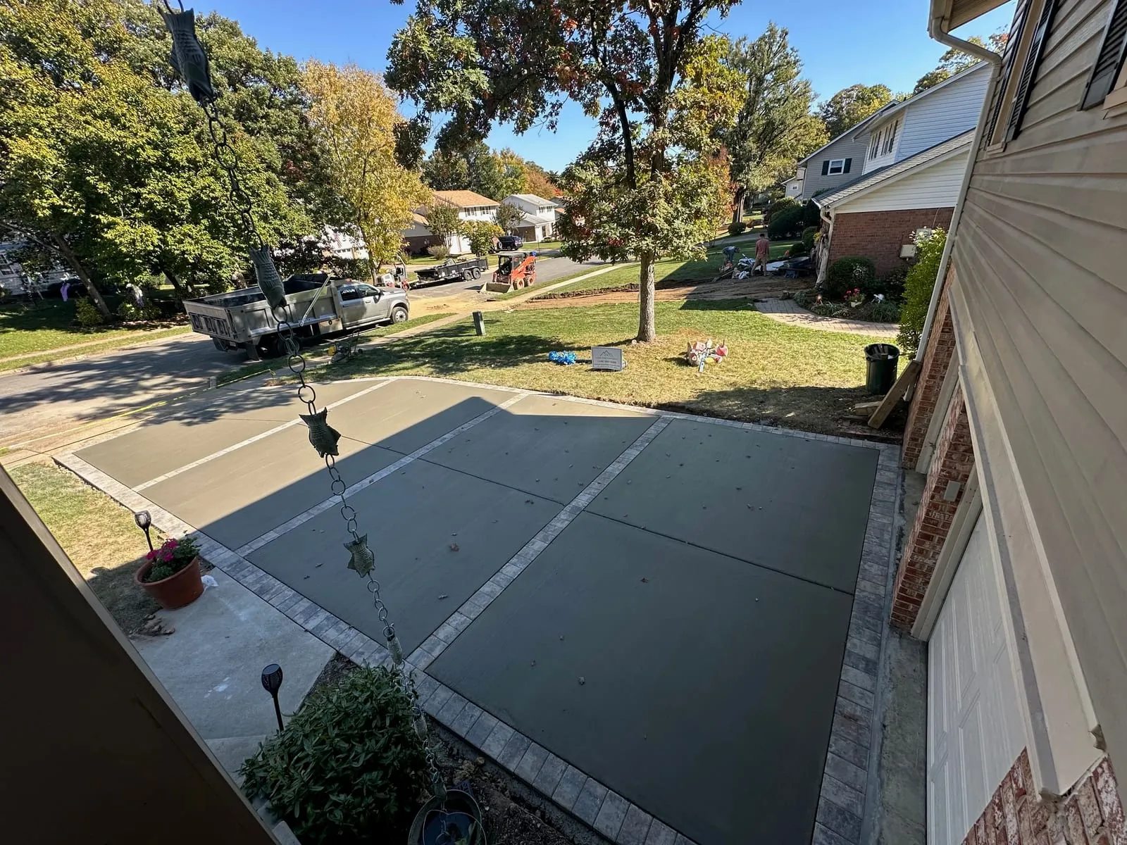 Gray concrete driveway with paver brick border framing the slab