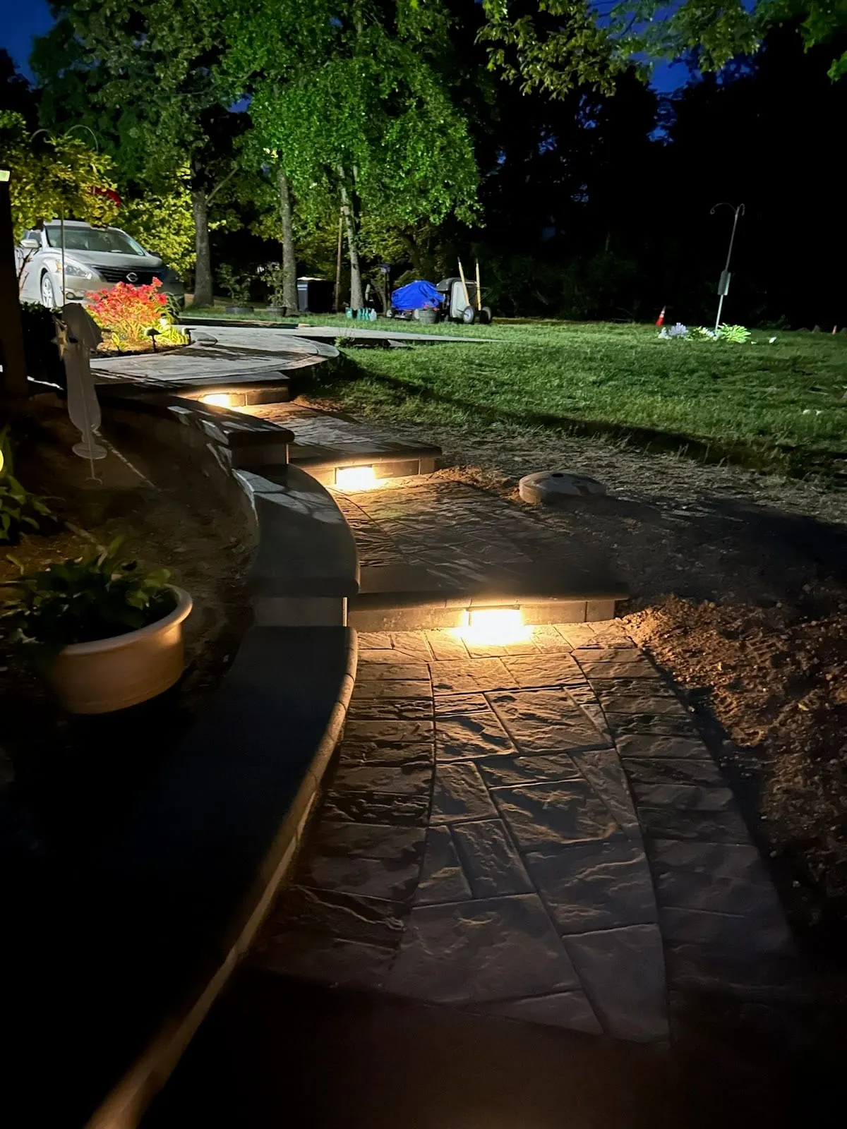 Stamped-stone walkway and steps at dusk lit by recessed riser lights