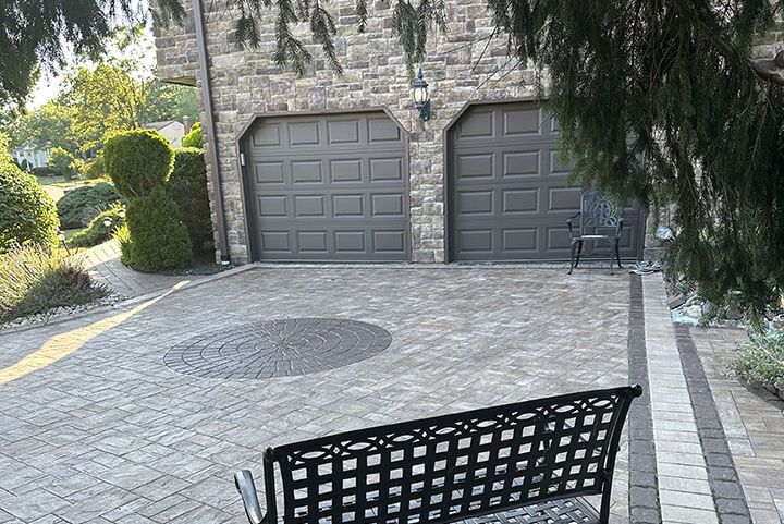 Twin-door garage clad in gray stacked stone veneer alongside a paver driveway.