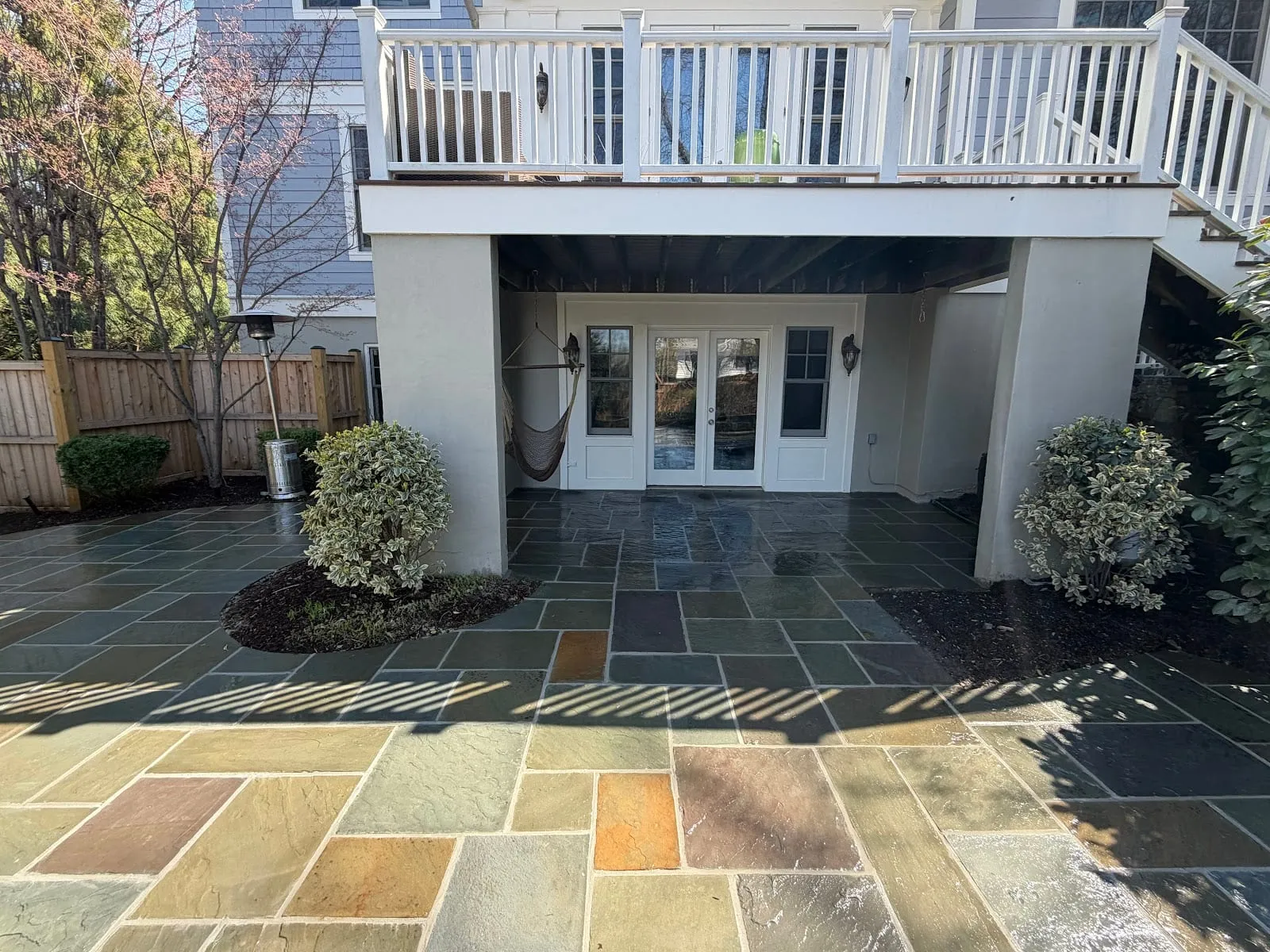 Multi-tone bluestone flagstone patio under a white deck with hammock