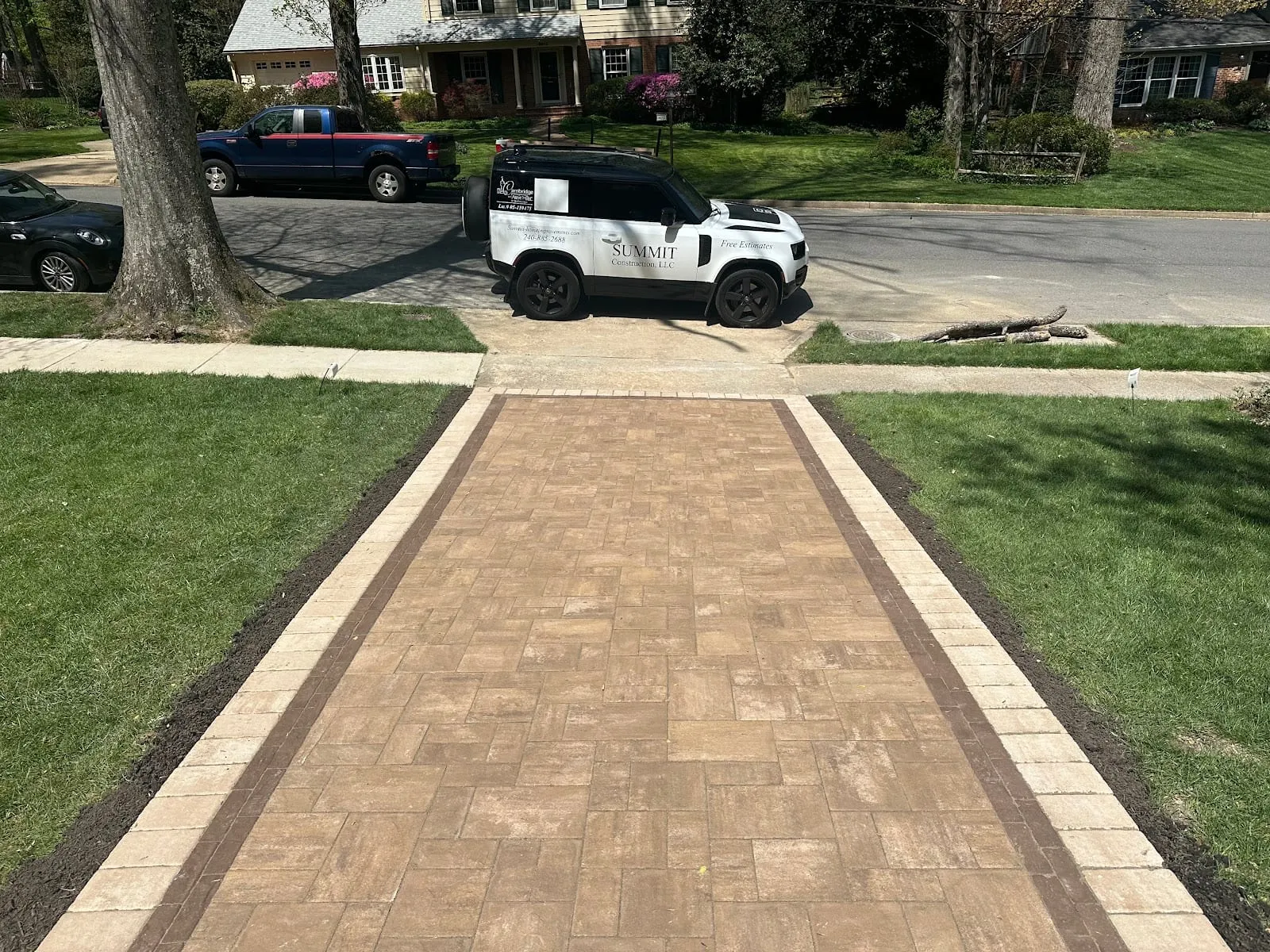 Wide tan herringbone paver walkway with branded Summit Land Rover at curb