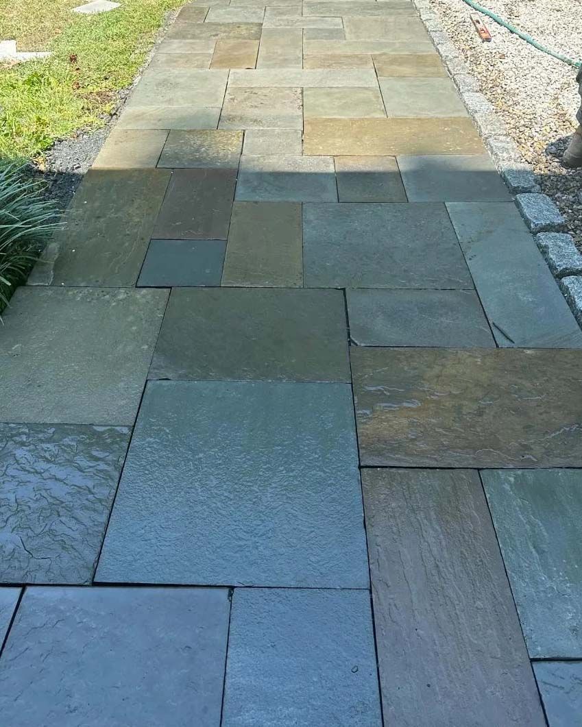 Close detail of wet bluestone flagstones laid in a tight joint pattern across a patio.